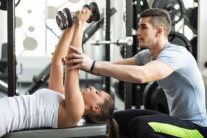 Fitness instructor exercising with his client at the gym